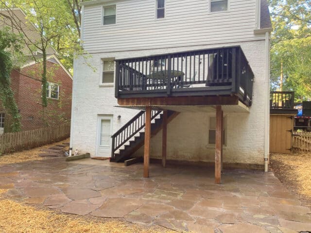 End result of a flagstone patio built in Kensington, MD. Angle shows patio underneath and extending beyond rear deck.