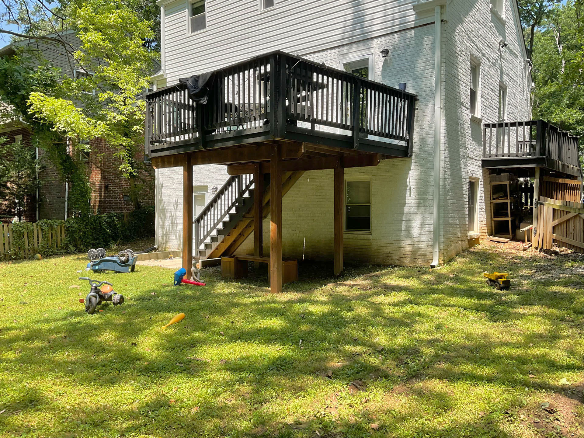 A backyard in Kensington MD before installation of a walkway and patio. Angle shows the backyard and rear deck.